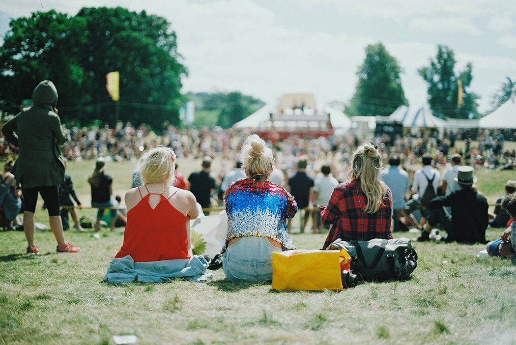 3 people sitting in a field at a concert